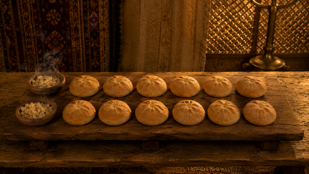 Twelve loaves of bread arranged in two rows of six on the gold table, evoking the priestly holy food of Leviticus 22